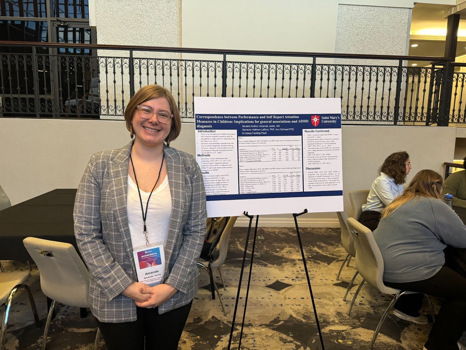 Student stands in front of poster describing research results in a conference room.