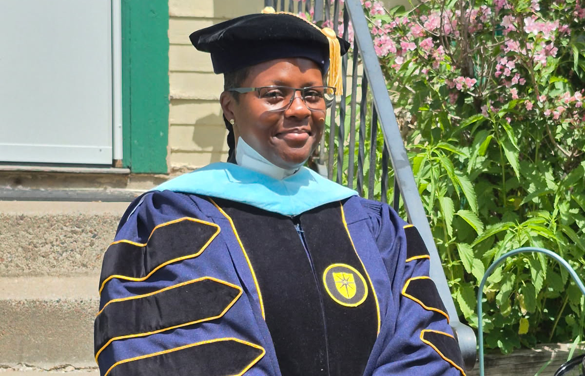 Lydia Majors-Roland, smiling, wearing cap and gown for graduation.